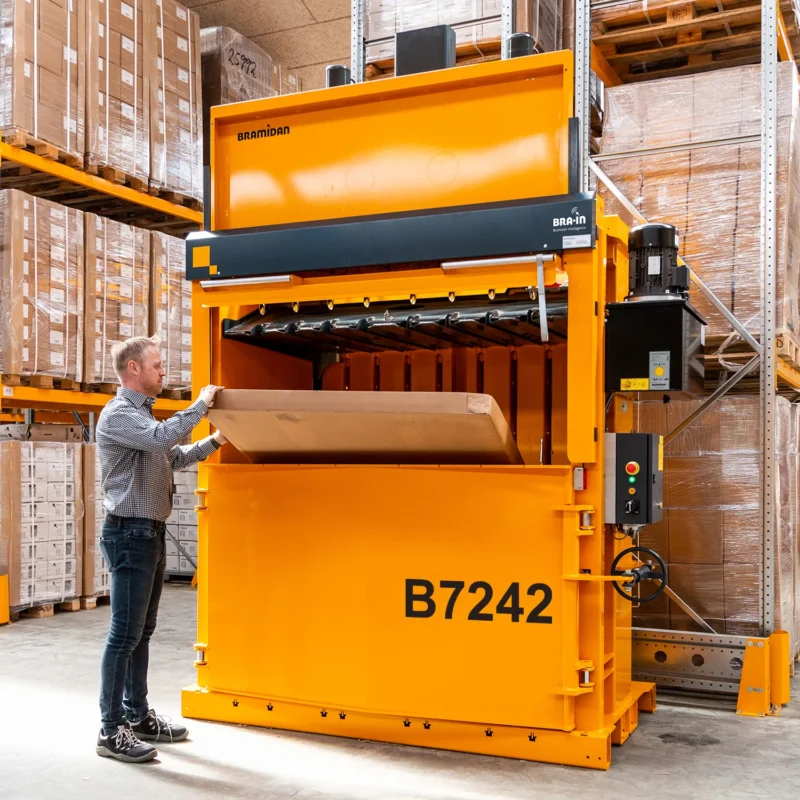 Man filling a B7242 baler with cardboard in a warehouse