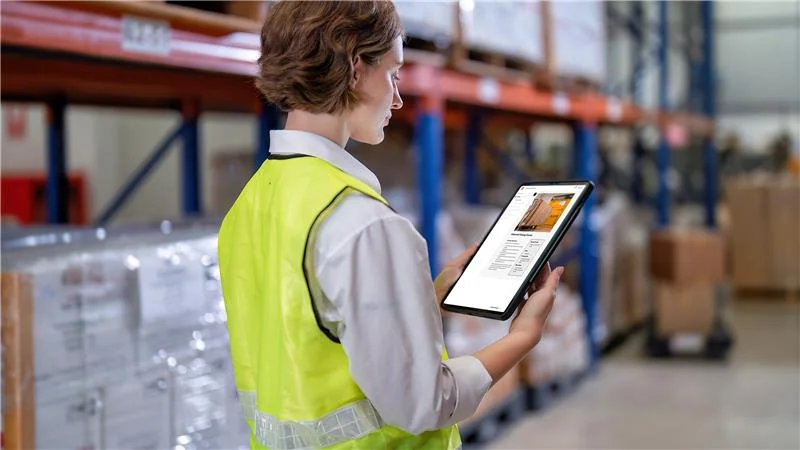 Woman in warehouse getting certified in operator training on iPad.